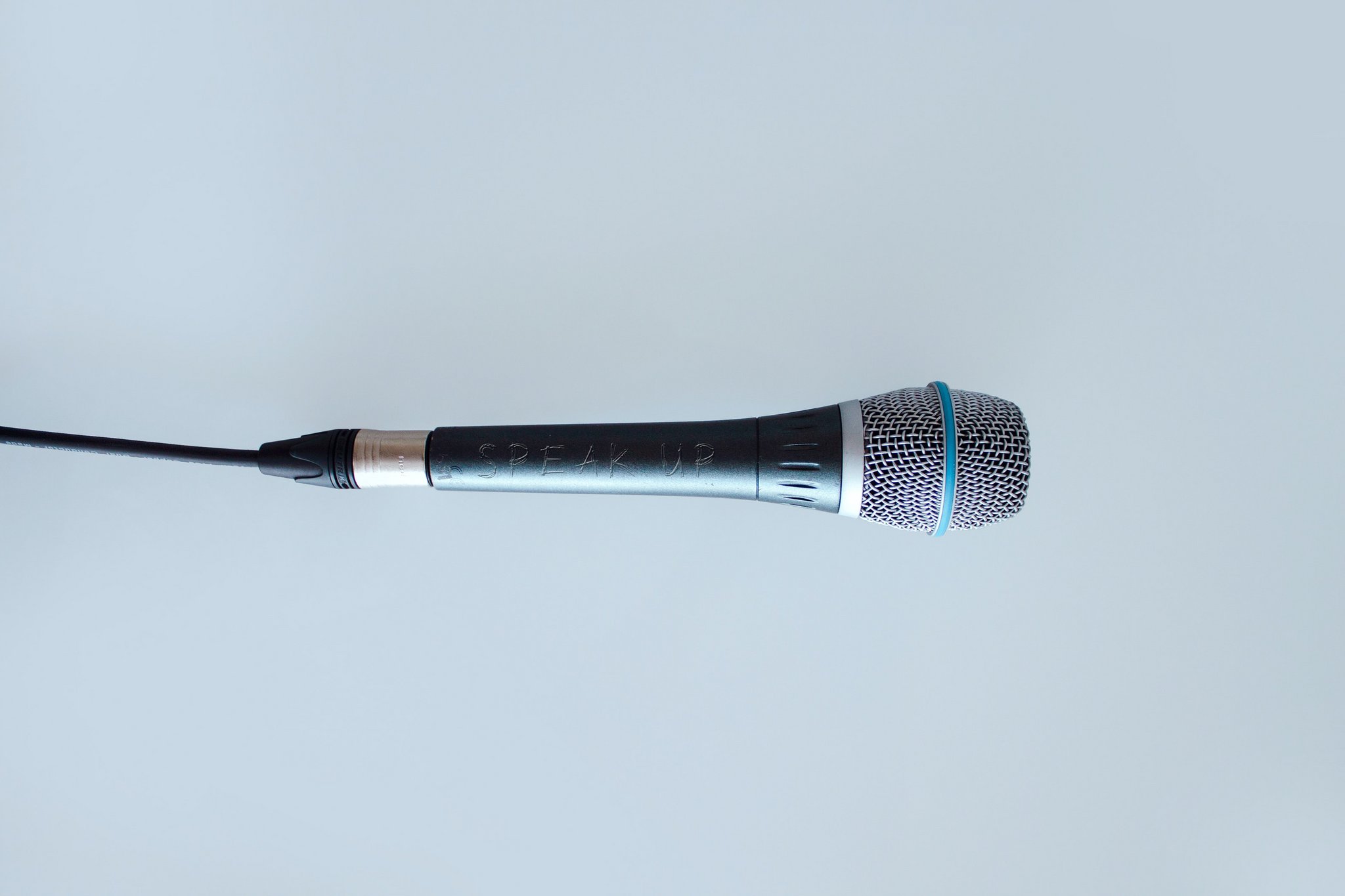 Das Bild zeigt ein Mikrofon, auf dessen Griff die Worte Speak Up eingeritzt sind