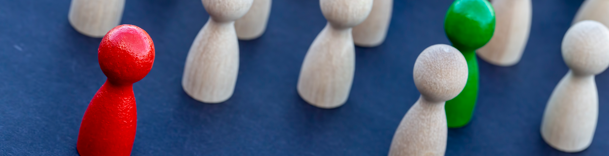 Das Bild zeigt Spielfiguren. Die meisten sind weiß. Eins ist rot und ein ist grün.