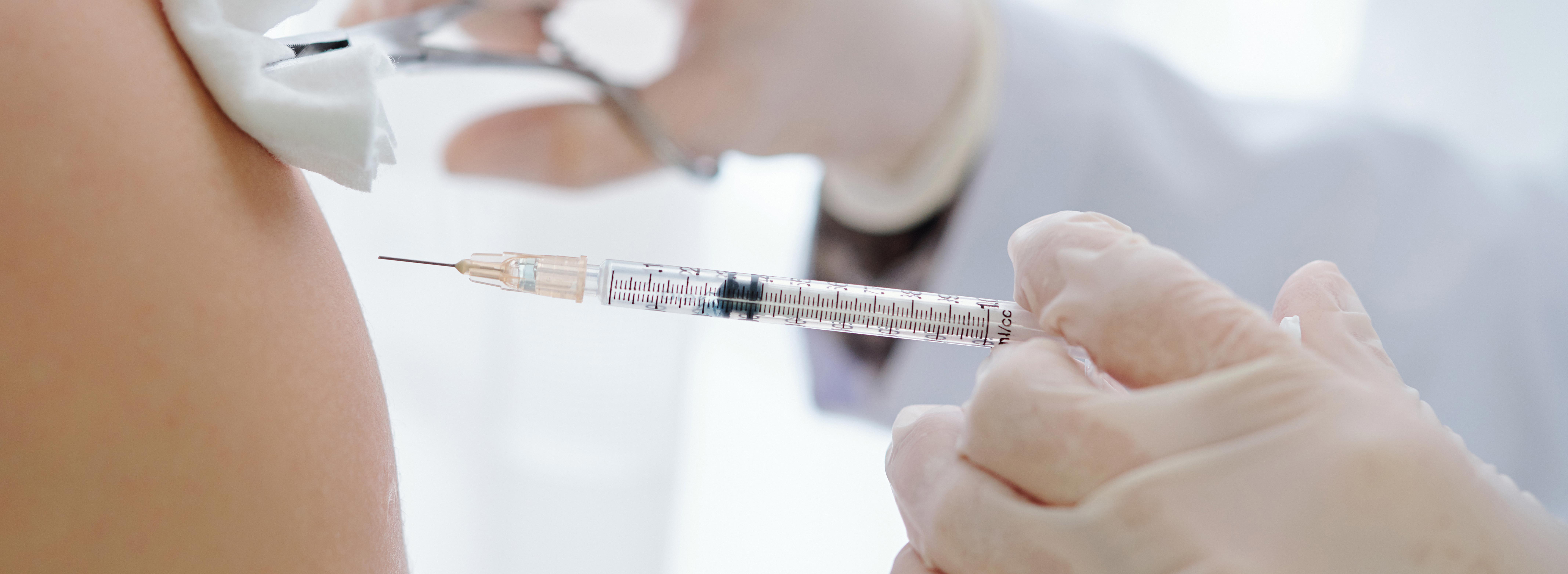 Das Bild zeigt eine Impfvergabe per Injektionsspritze