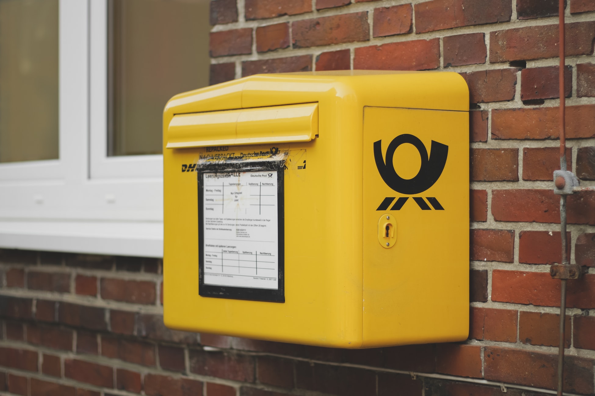Das Bild zeigt einen gelben Briefkastenmit dem Logo der Deutschen Post